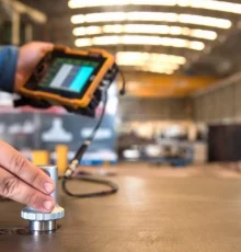 Quality control engineer measuring steel thickness with digital caliper in factory